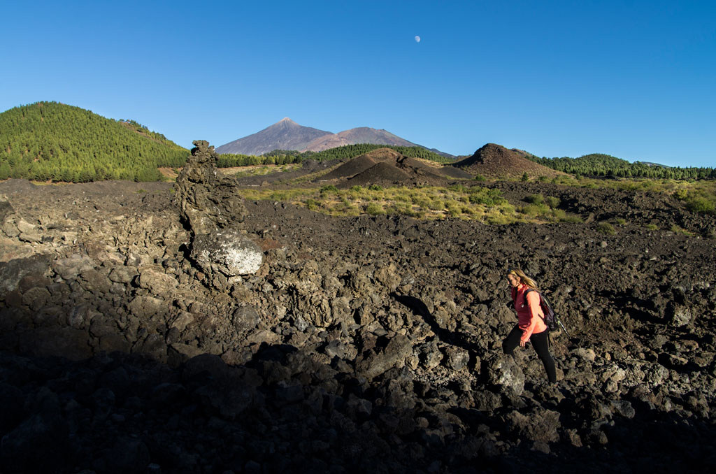 Personne marchant sur un terrain volcanique près du mont Teide, à Tenerife, sous un ciel dégagé.