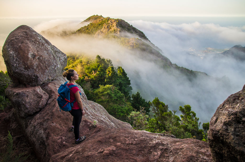 Une personne avec un sac à dos observe les montagnes et les nuages à Tenerife.