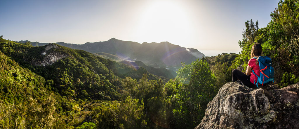 Personne avec un sac à dos regardant le paysage montagneux de Tenerife au coucher du soleil.