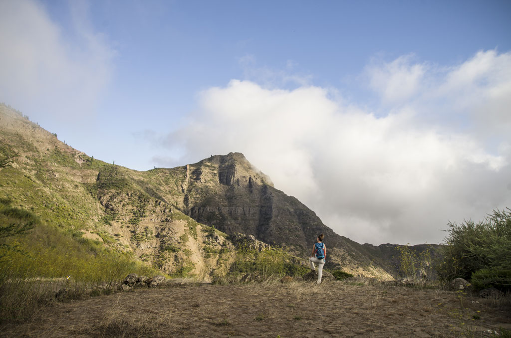 Personne marchant devant les montagnes de Tenerife sous un ciel partiellement nuageux.