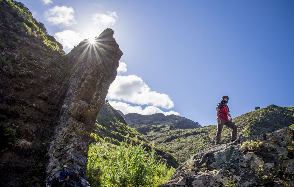 Personne en randonnée dans le ravin de Masca, à Tenerife, avec le soleil brillant derrière lui.