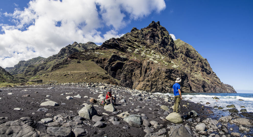 Des gens sur une plage de sable noir avec des montagnes sur la côte de Tenerife.