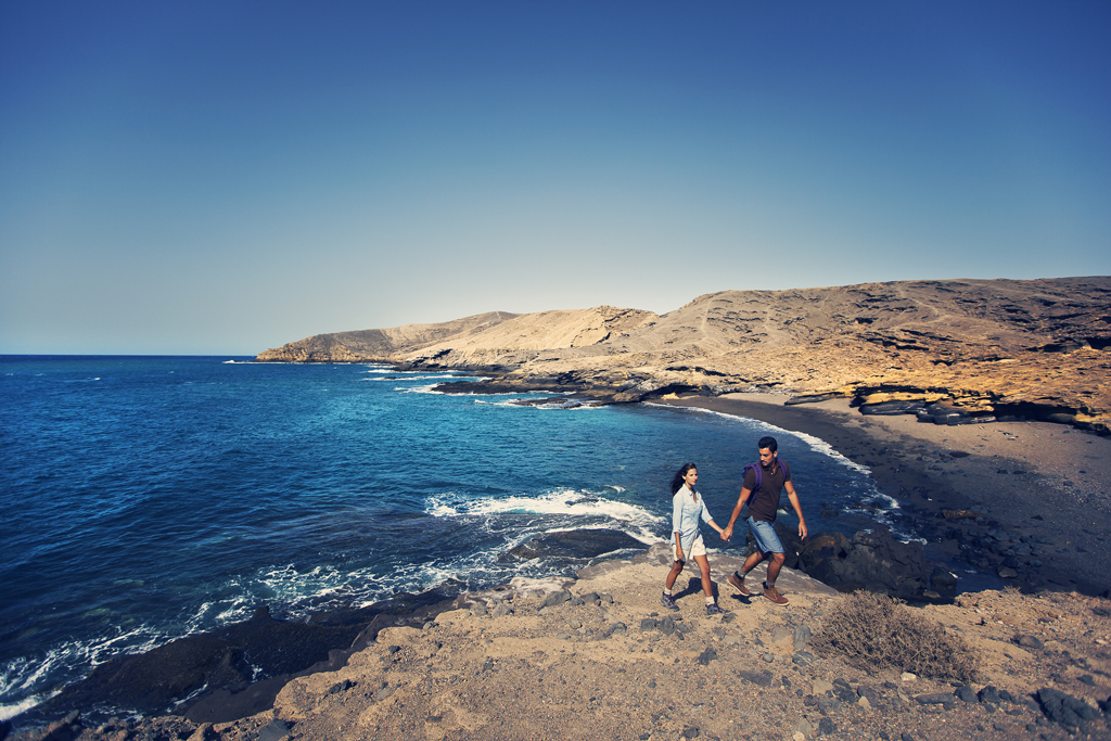 Couple marchant au bord de la mer dans un paysage côtier de Tenerife.
