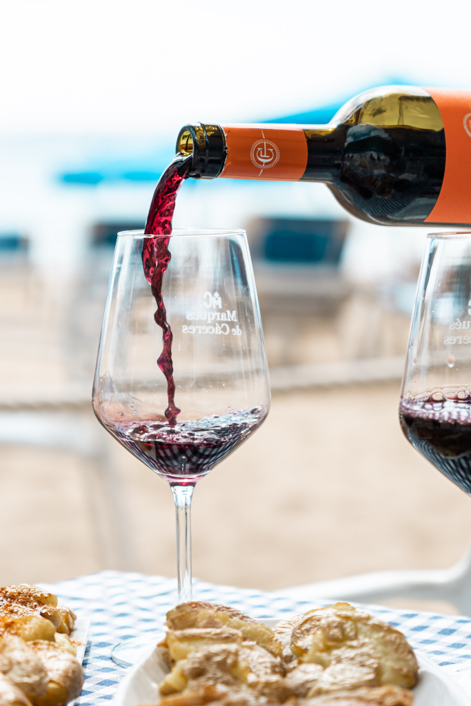 Du vin rouge versé dans un verre avec des gâteaux sur une table de plage à Tenerife.