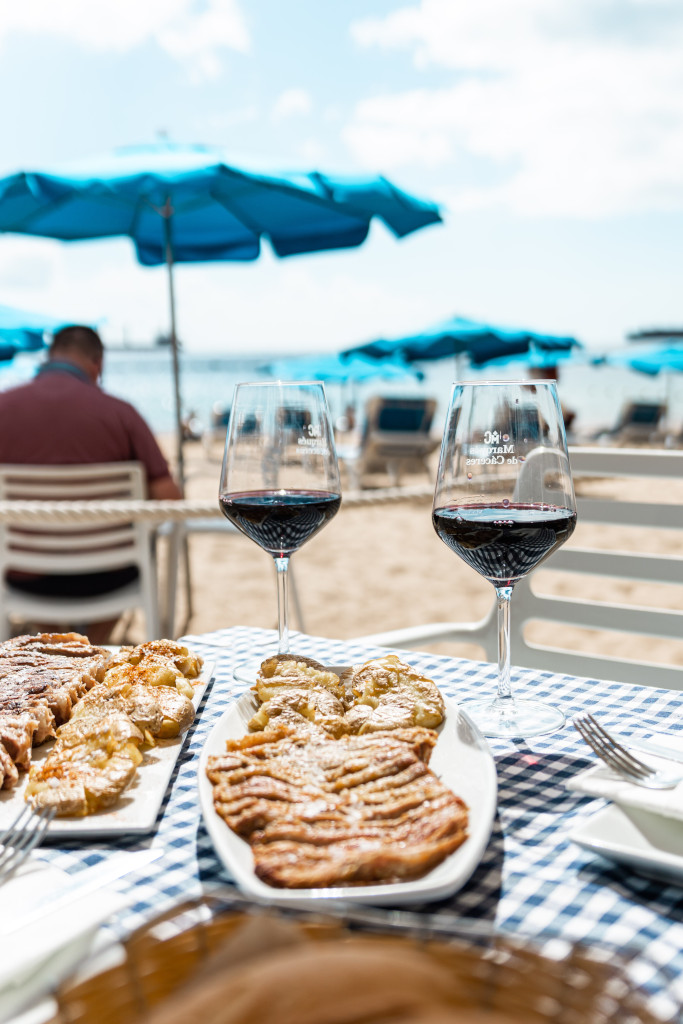 Des verres de vin et de la nourriture sur la plage avec des parasols bleus à Tenerife.