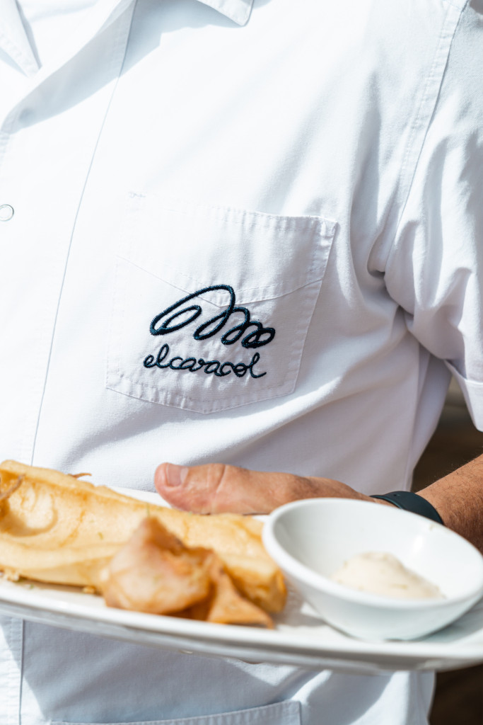 Serveur en chemise d’escargot blanc portant une assiette de nourriture.