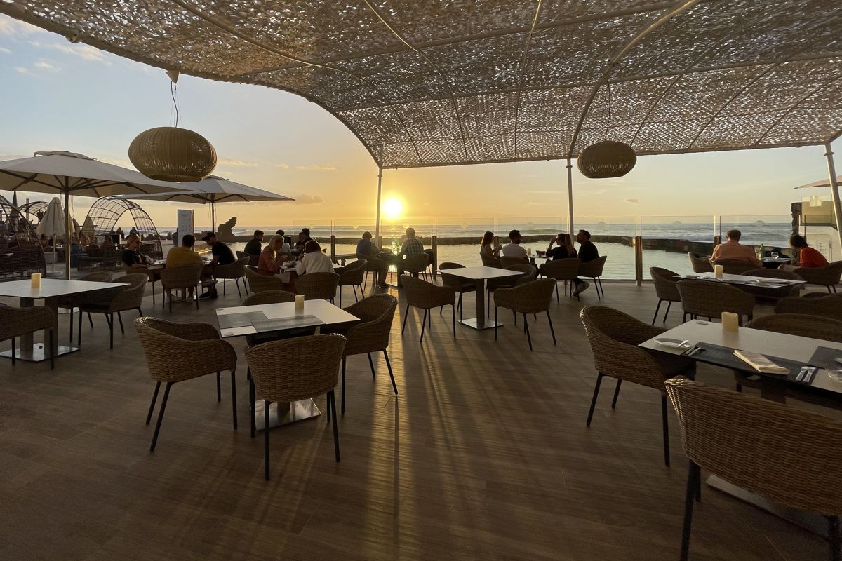 Des gens dînant au coucher du soleil sur une terrasse surplombant la mer à Tenerife.