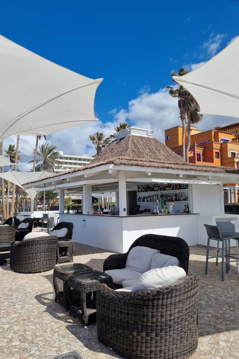 Bar en plein air avec toit de chaume, tables et chaises à Tenerife.