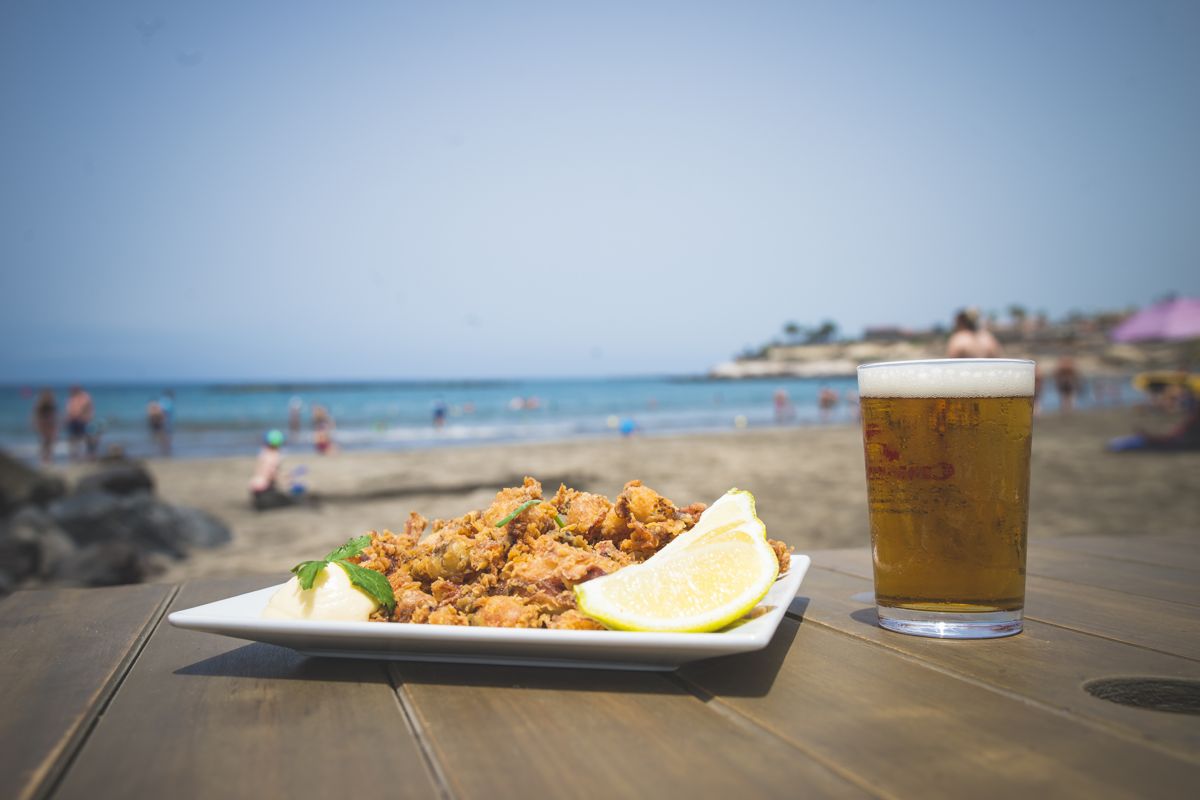 Assiette de nourriture et verre de boisson sur une table sur une plage à Tenerife.