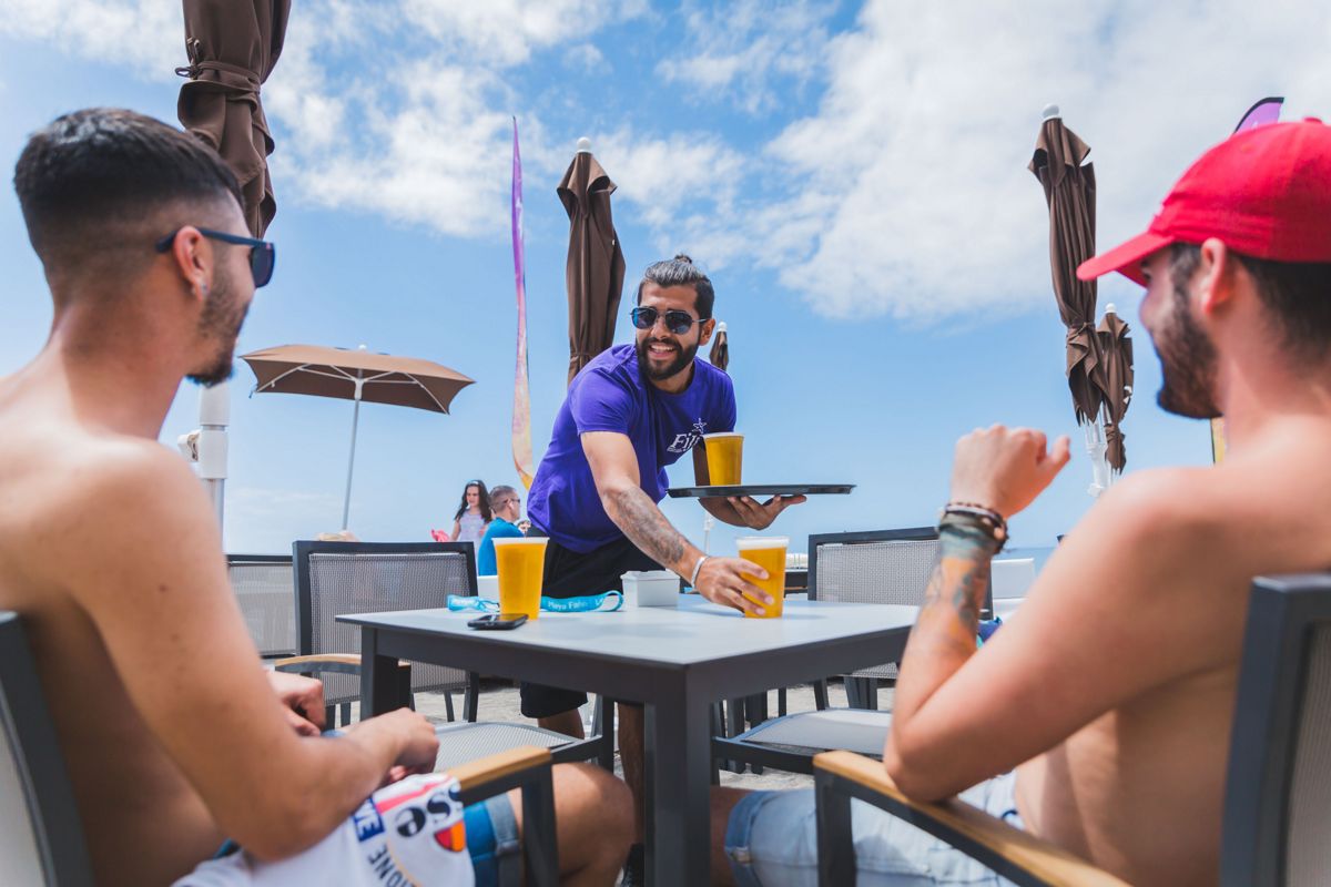 Serveur servant des bières à deux hommes sur une terrasse à Tenerife.