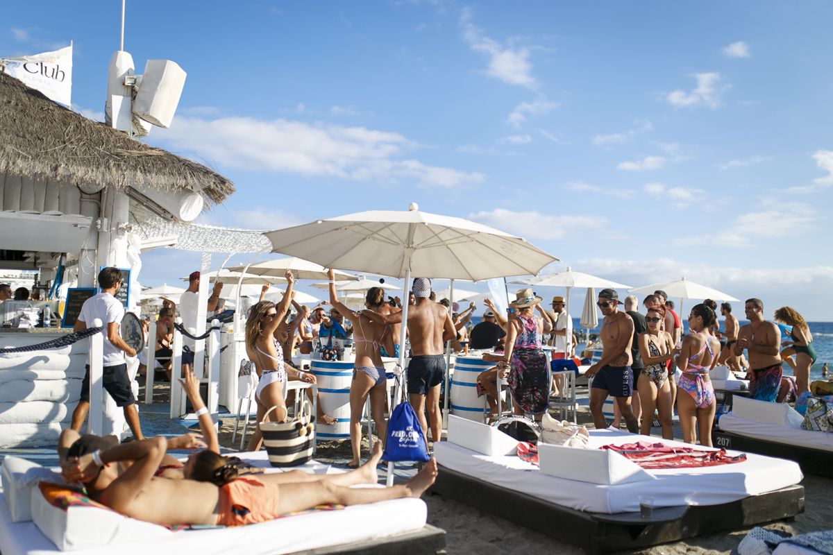 Des gens profitant d’un beach club à Tenerife sous des parasols.