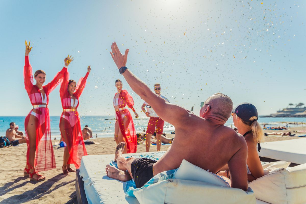 Des gens profitant de la plage avec des danseurs à Puerto de la Cruz, Tenerife.