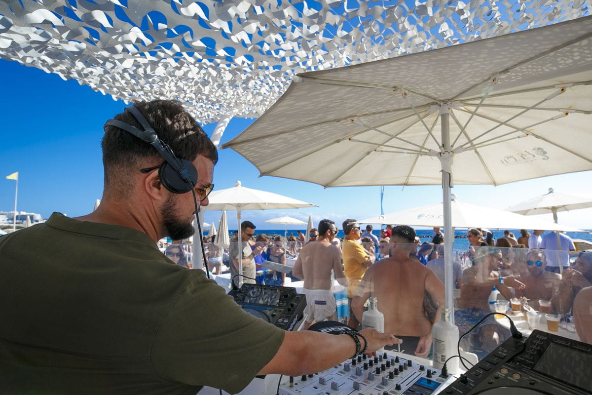 DJ lors d’un événement en plein air sur la plage de Tenerife devant un public qui s’amuse.