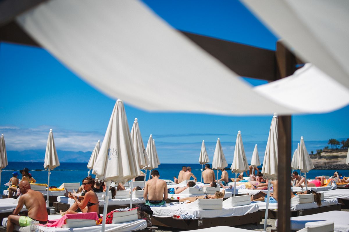Des gens prenant le soleil dans des hamacs sous des parasols sur la plage de Tenerife.