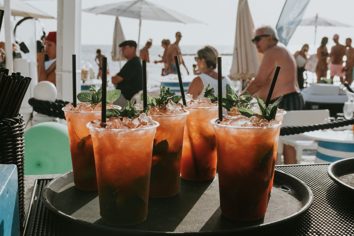 Des verres de cocktails à la menthe et glace sur une plage animée à Tenerife.