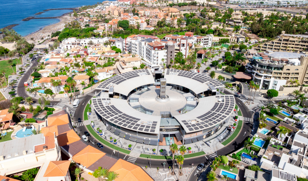 Vue aérienne du centre commercial Plaza del Duque à Tenerife, entourée de bâtiments et de mer.