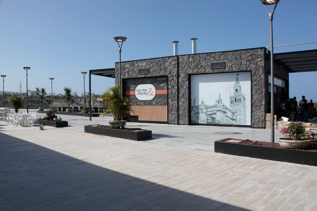 Locaux à Tenerife avec une enseigne Tex-Mex & Company et une fresque d’un bâtiment historique.