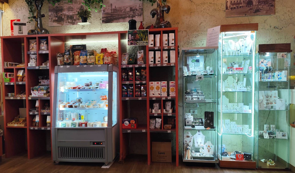 Des étagères avec des snacks, un frigo avec des produits laitiers et des vitrines avec des bijoux dans un magasin à Tenerife.