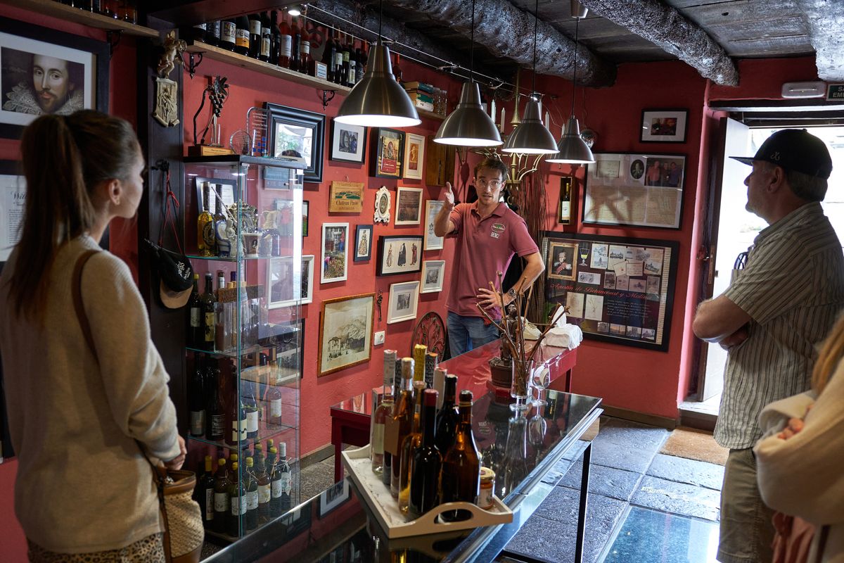 Un homme expliquant les vins aux touristes, entouré de bouteilles et de décorations à Tenerife.
