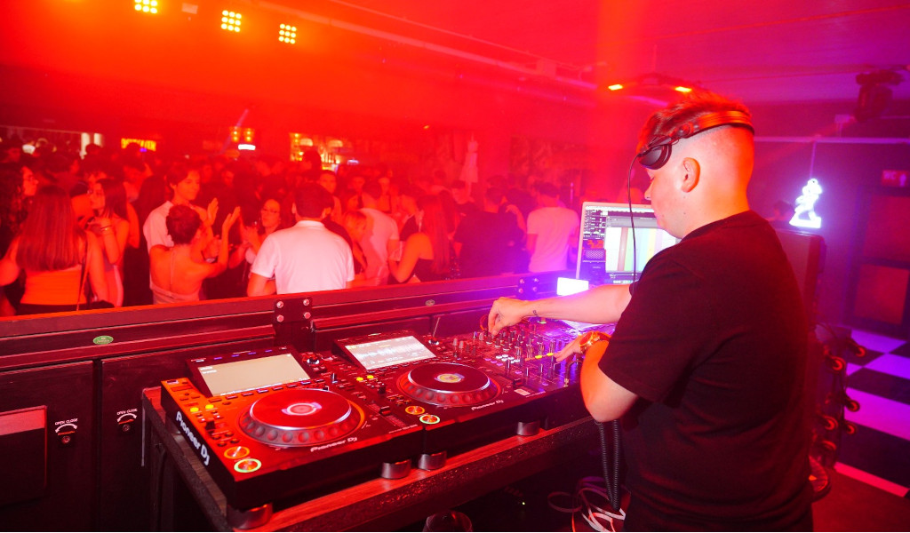 DJ animant une soirée dans une boîte de nuit à Tenerife avec des lumières rouges et un public dansant.