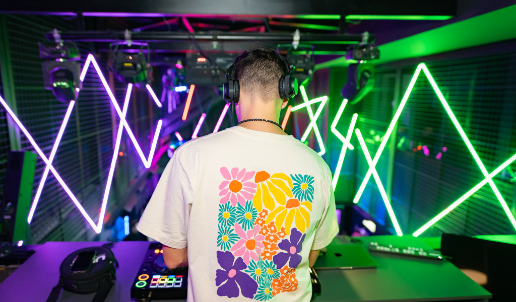 DJ en t-shirt fleuri mélange de la musique dans le club de Tenerife avec des néons.