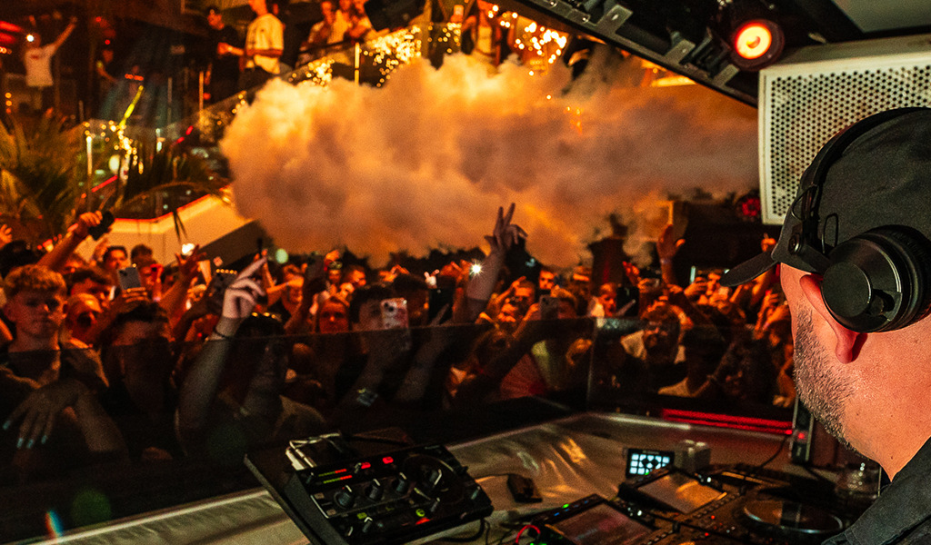 DJ jouant en live devant une foule animée dans un club à Tenerife.
