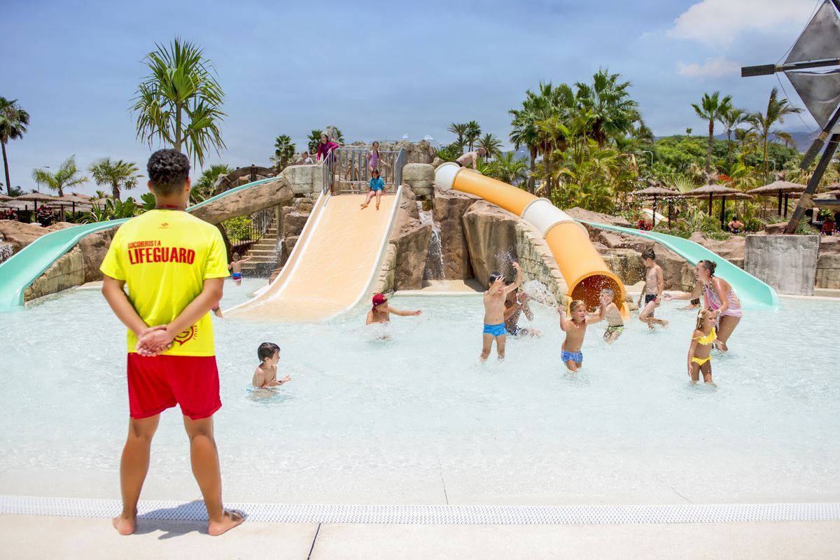 Maître-nageur regardant des enfants jouer sur les toboggans au parc aquatique de Tenerife.