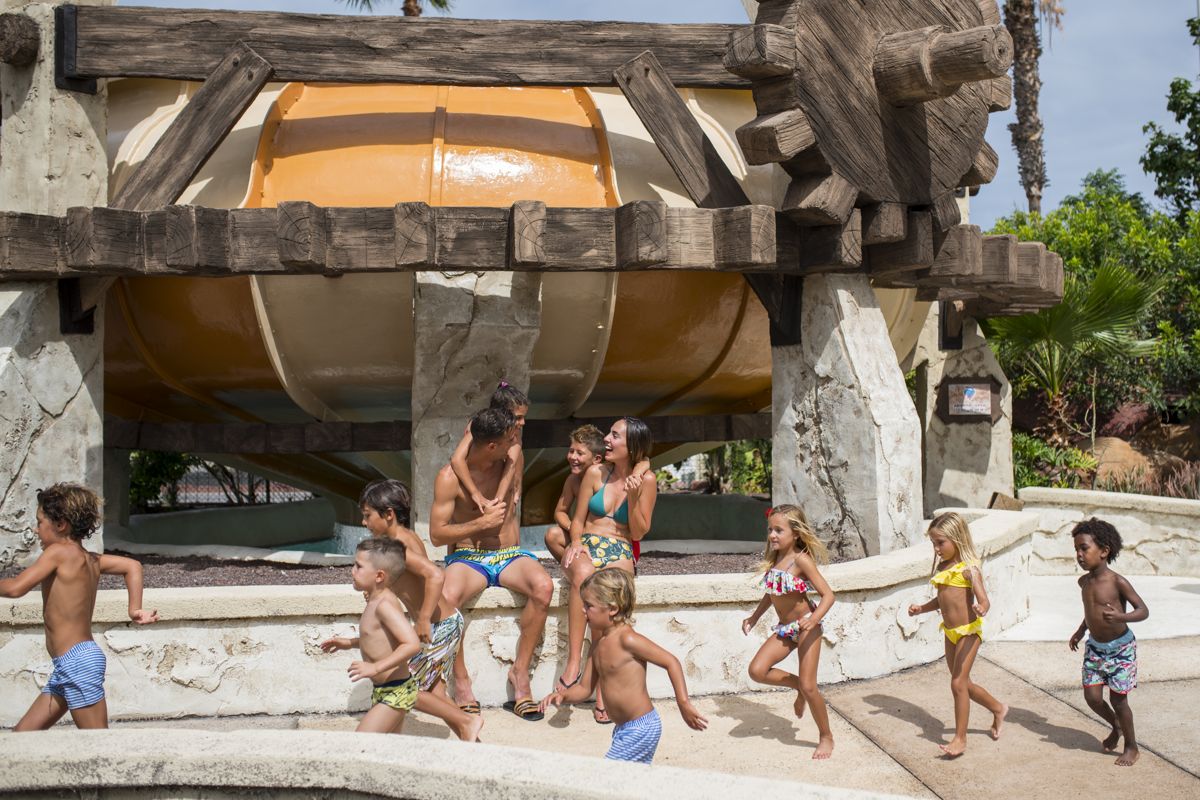 Des enfants jouant dans un parc aquatique à Tenerife sous un grand toboggan.
