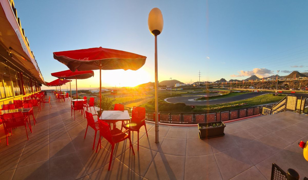 Terrasse de restaurant avec tables rouges et vue sur le coucher du soleil sur un circuit à Tenerife.