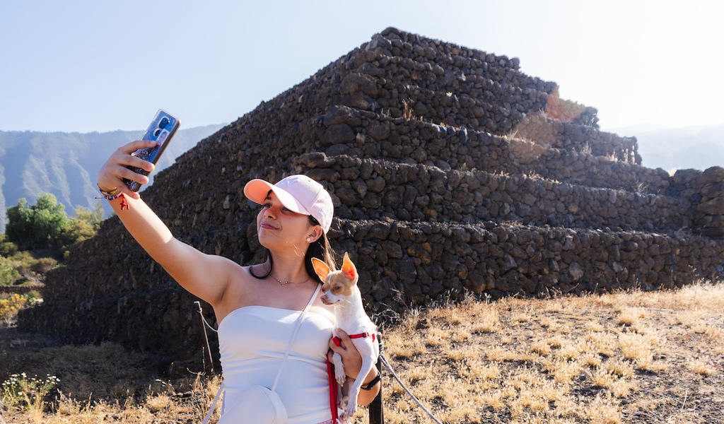 Personne prenant un selfie avec un chien devant les pyramides de Güímar à Tenerife.