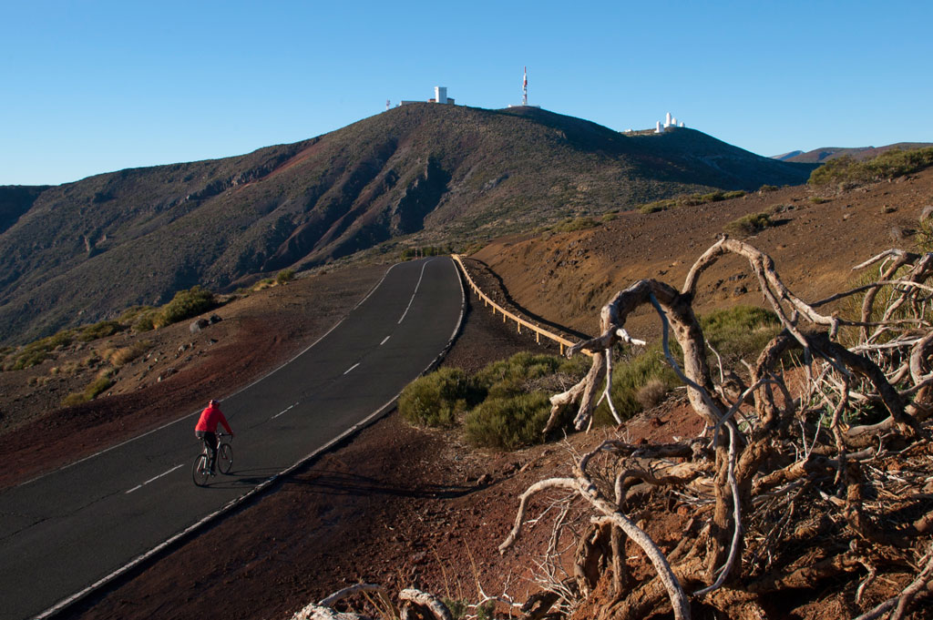 Cycliste sur route dans le parc national de la Teide, Tenerife, avec des collines en arrière-plan.