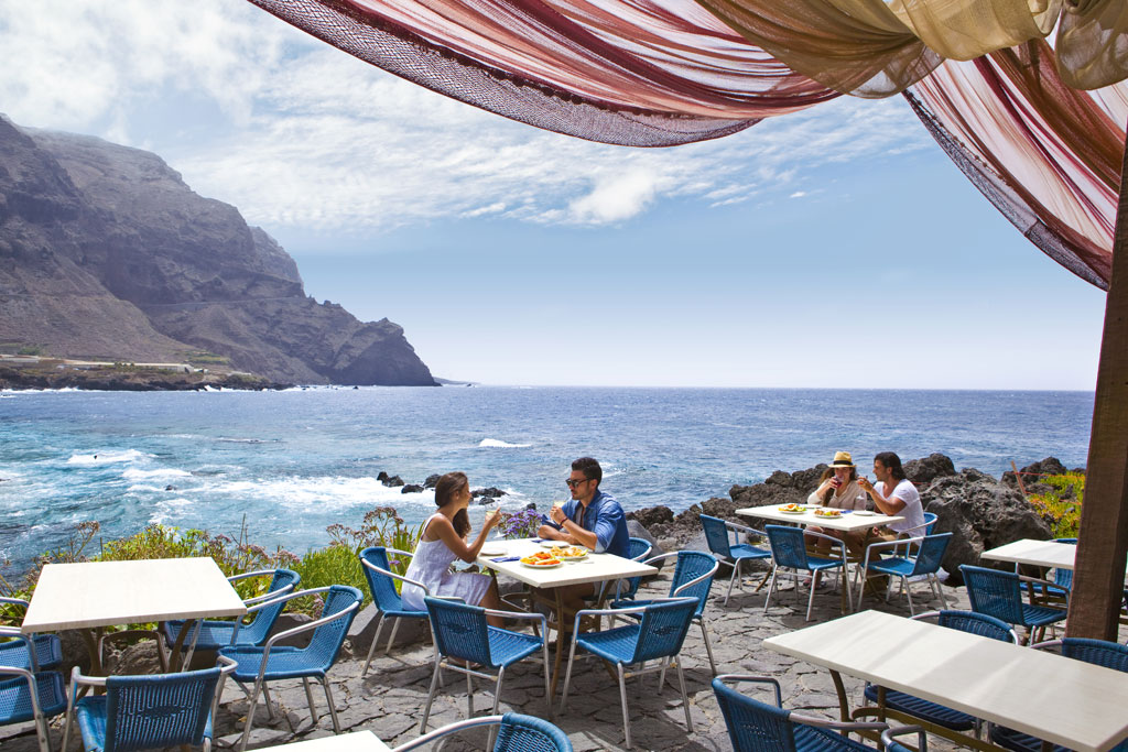 Terrasse en bord de mer à Tenerife où les gens mangent sous un ciel dégagé.