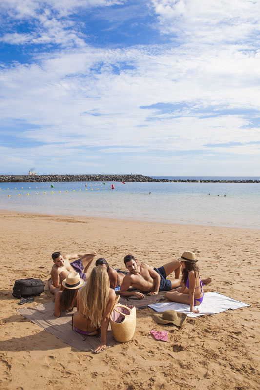 Groupe d’amis sur la plage de Las Teresitas, à Tenerife, profitant du soleil.