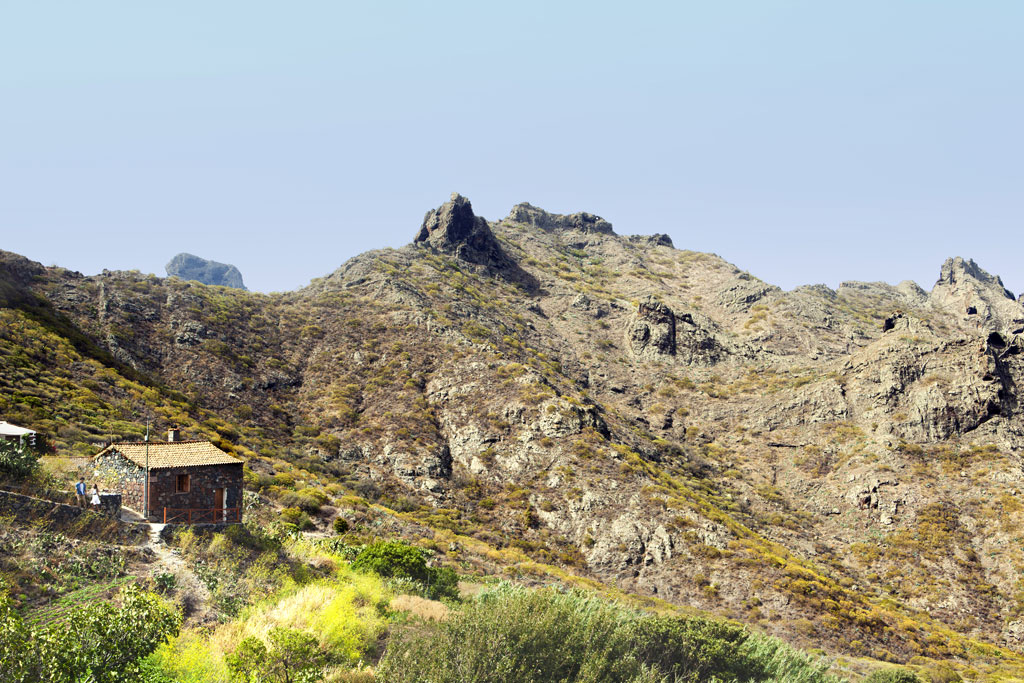 Maison en pierre dans le paysage montagneux de Masca, Tenerife, avec une végétation tout autour.