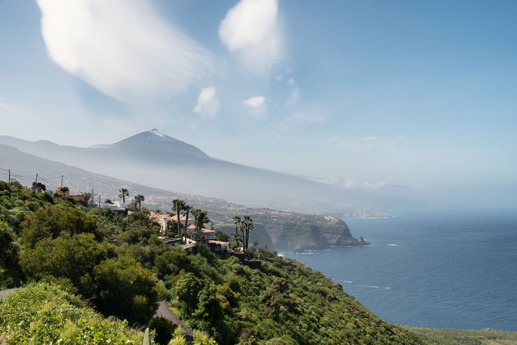 Vue sur le mont Teide depuis la côte de Tenerife, avec la mer et la végétation au premier plan.