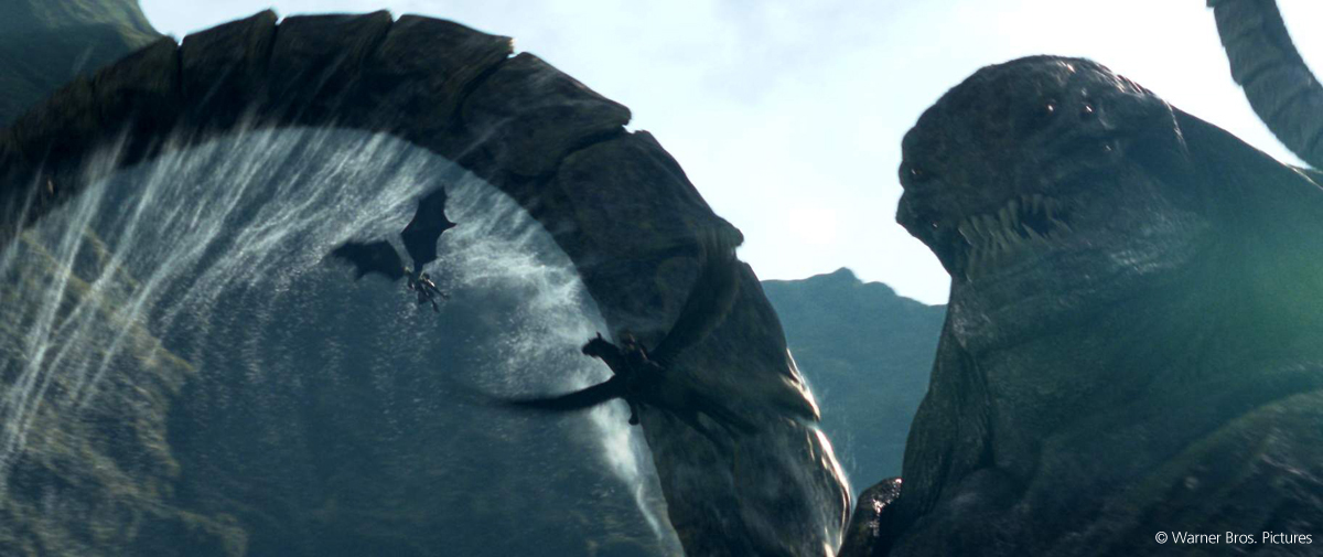 Créature géante en forme de monstre marin devant des dragons volant entre des montagnes et une grande vague.