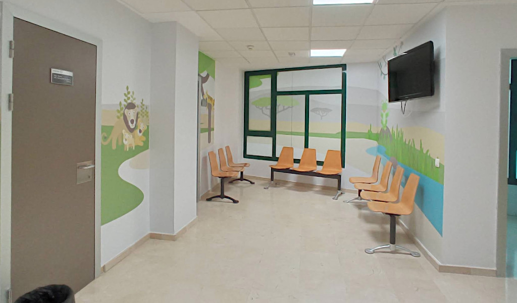 Salle d’attente avec chaises orange et fresques colorées à Tenerife.