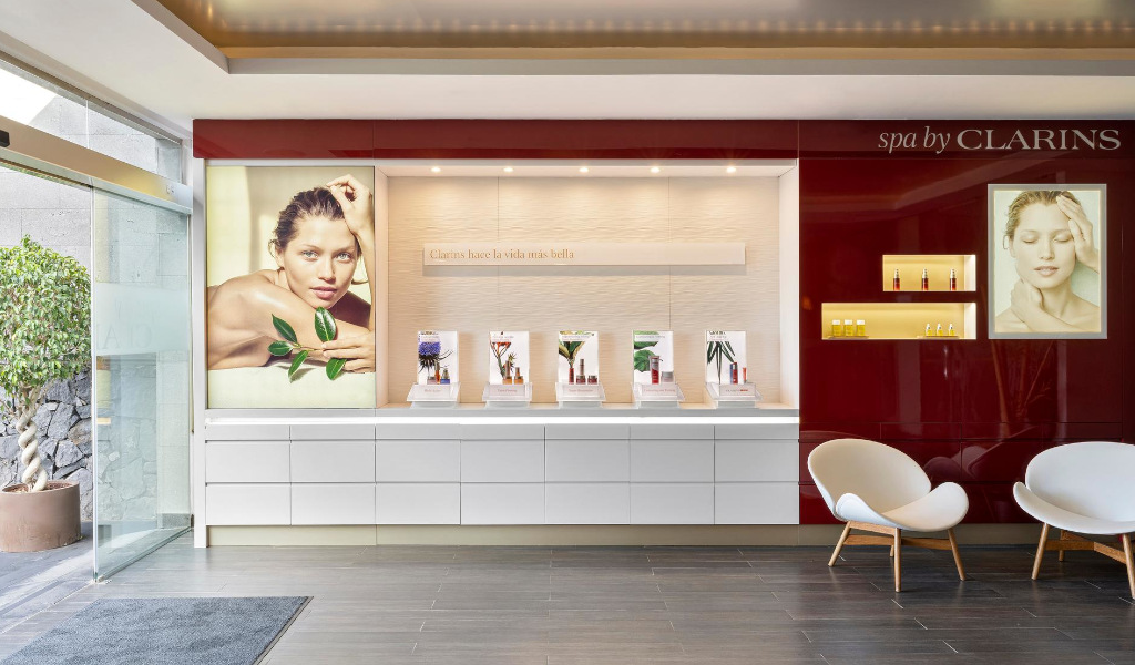 Accueil du spa Clarins à Tenerife avec affiches de modèles et de produits. Texte : Les clarines rendent la vie plus belle.