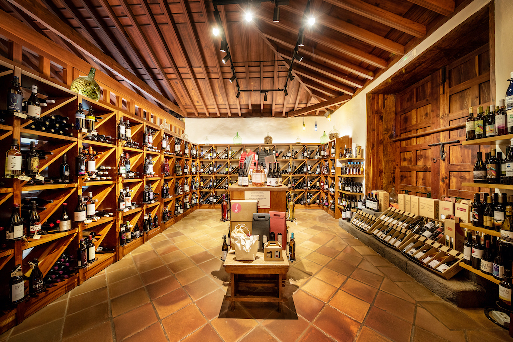 Cave à vin à Tenerife avec des étagères remplies de bouteilles de vin et un plafond en bois.