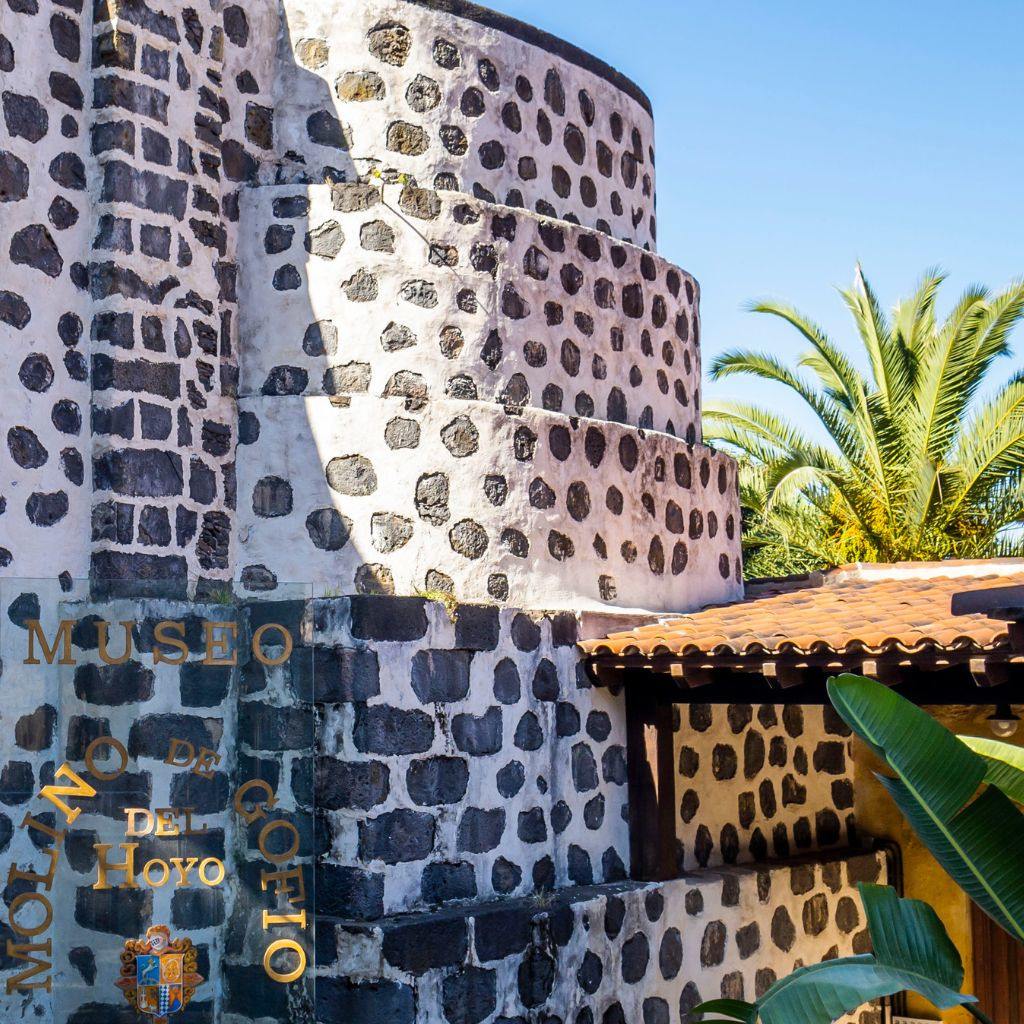 Le moulin Gofio del Hoyo à Tenerife avec des palmiers en arrière-plan.
