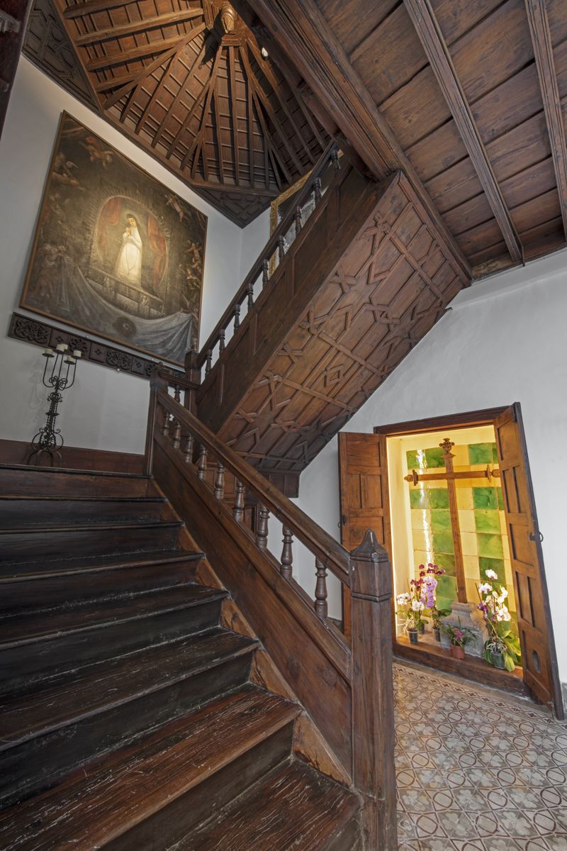 Escalier en bois avec peinture religieuse et vitraux dans une maison à Tenerife.