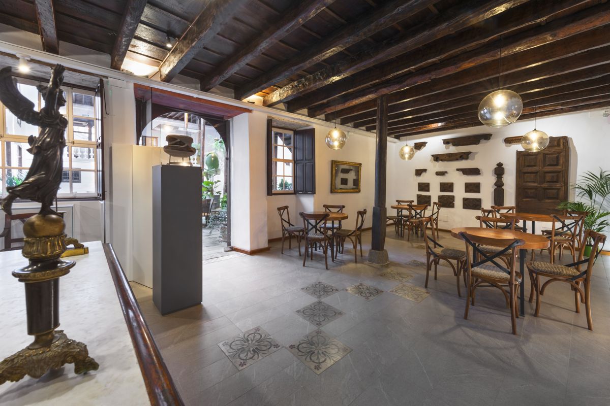 Intérieur d’un café historique à Tenerife avec des tables en bois et une décoration classique.