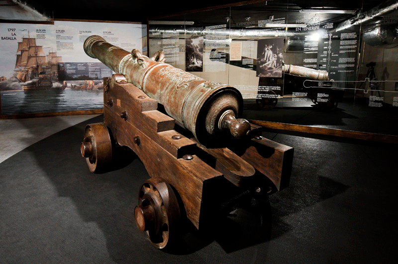 Un ancien canon exposé dans un musée à Tenerife, avec des panneaux d’information derrière.