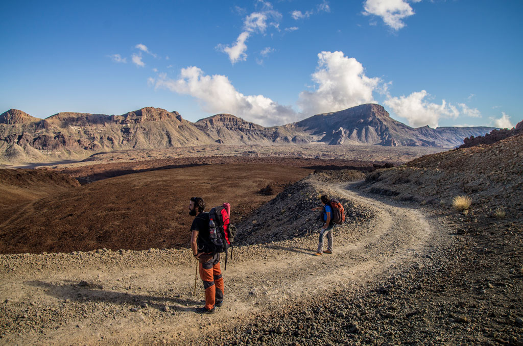 Sentier de montagne sur la Teide, Tenerife, avec deux personnes marchant sous un ciel bleu.