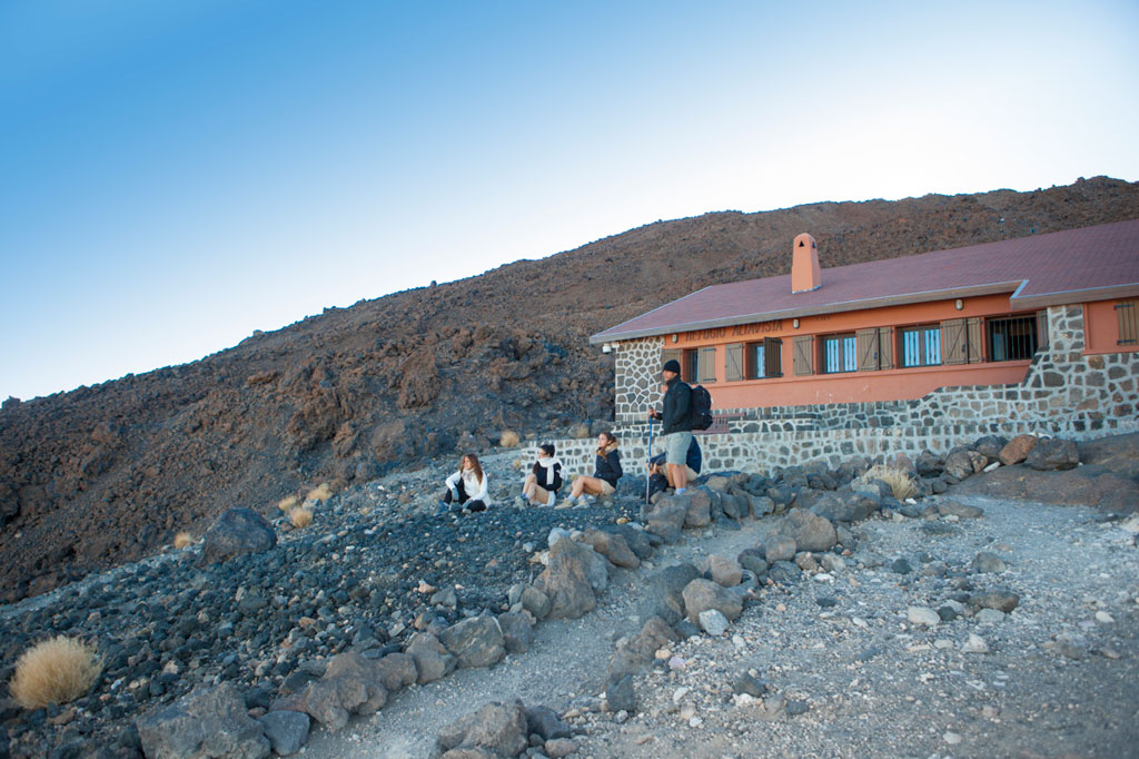 Des personnes se reposant devant le refuge d’Altavista dans le parc national du Teide, à Tenerife.