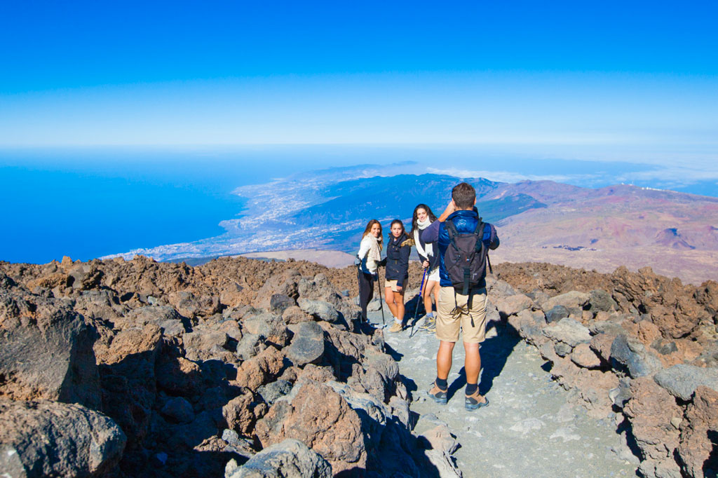 Groupe de personnes sur un sentier rocheux avec vue sur la mer et les paysages de Tenerife.