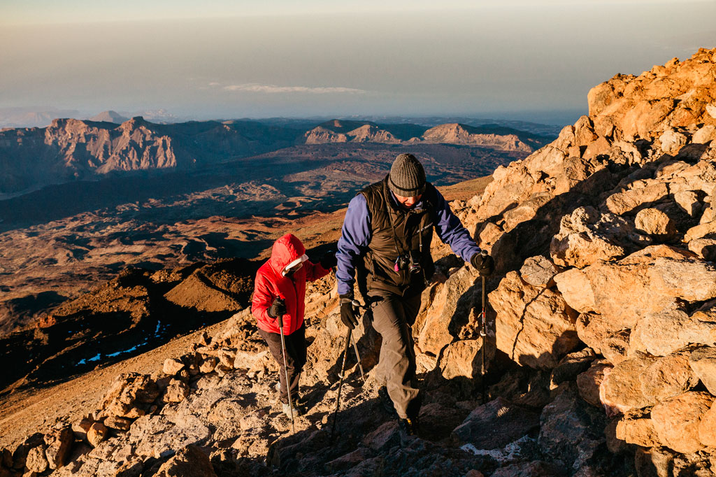 Des gens grimpant sur le mont Teide, à Tenerife, avec un paysage montagneux en arrière-plan.