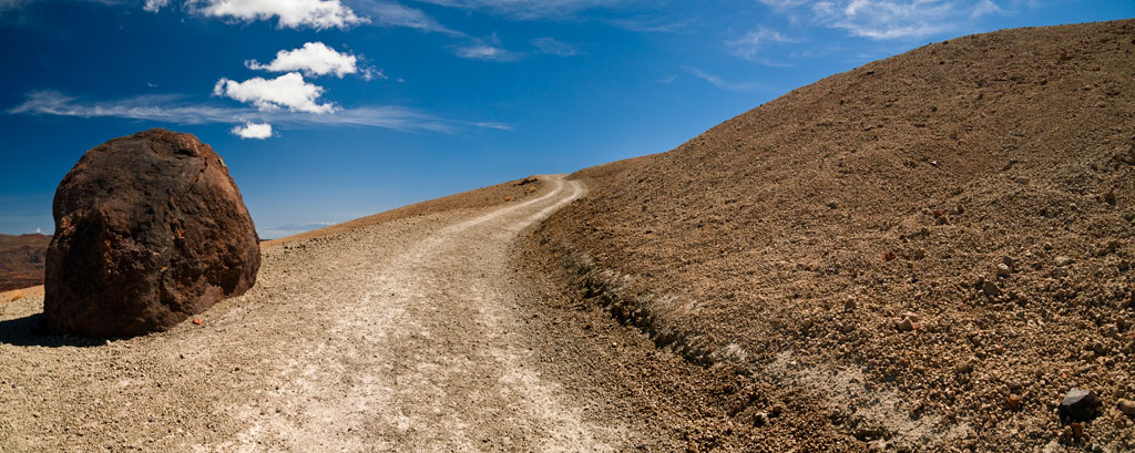 Sentier avec de grands rochers dans un paysage aride et un ciel bleu à Tenerife.