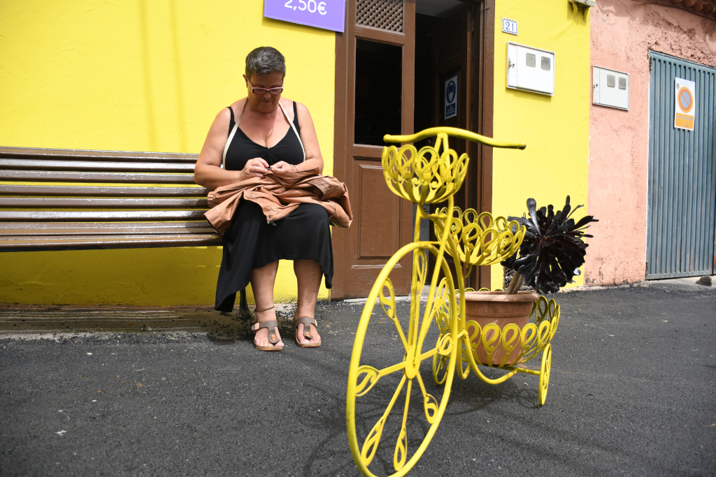 Femme assise sur un banc à côté d’un vélo décoratif à Tenerife.