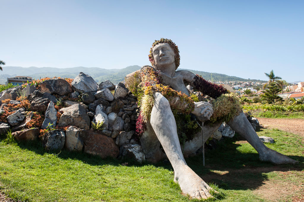 Sculpture d’une femme assise couverte de plantes dans un parc à Tenerife.